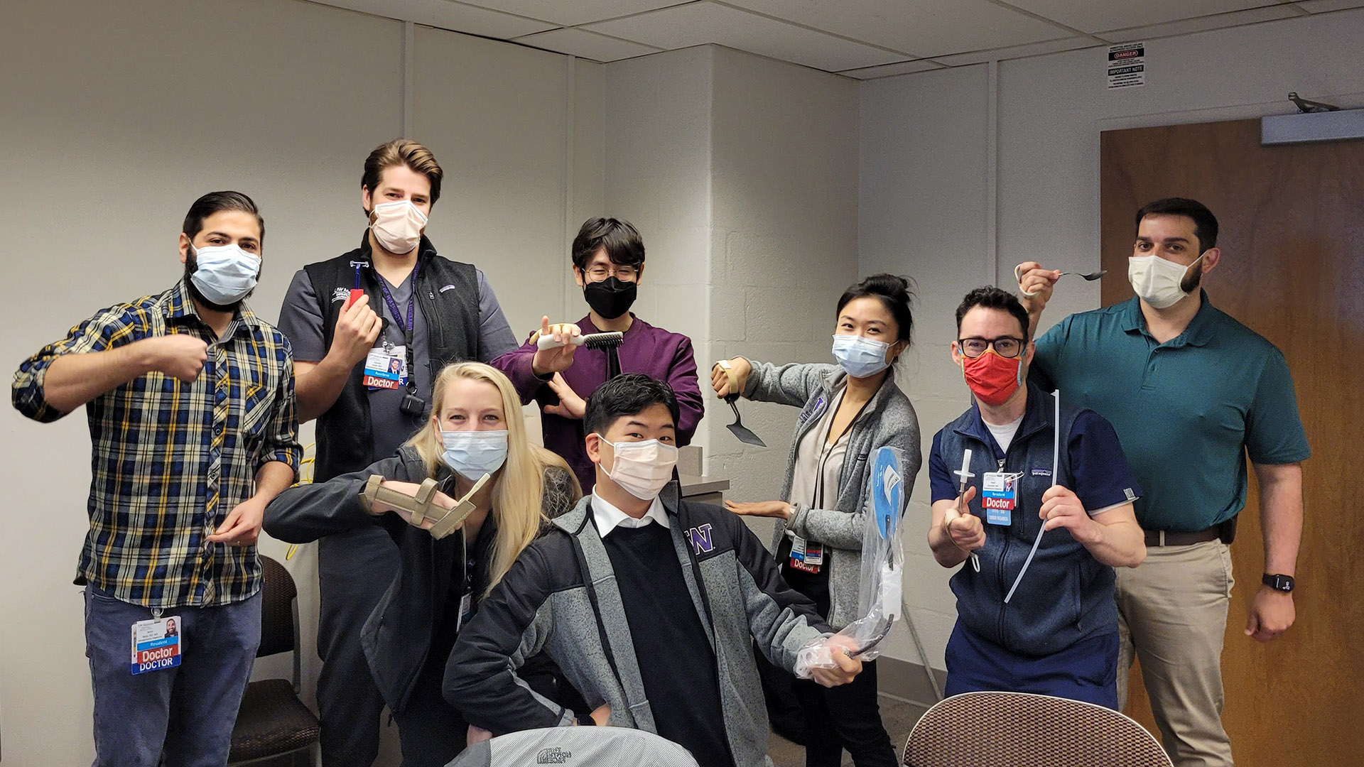A group of residents pose wearing wrist braces and holding household items.