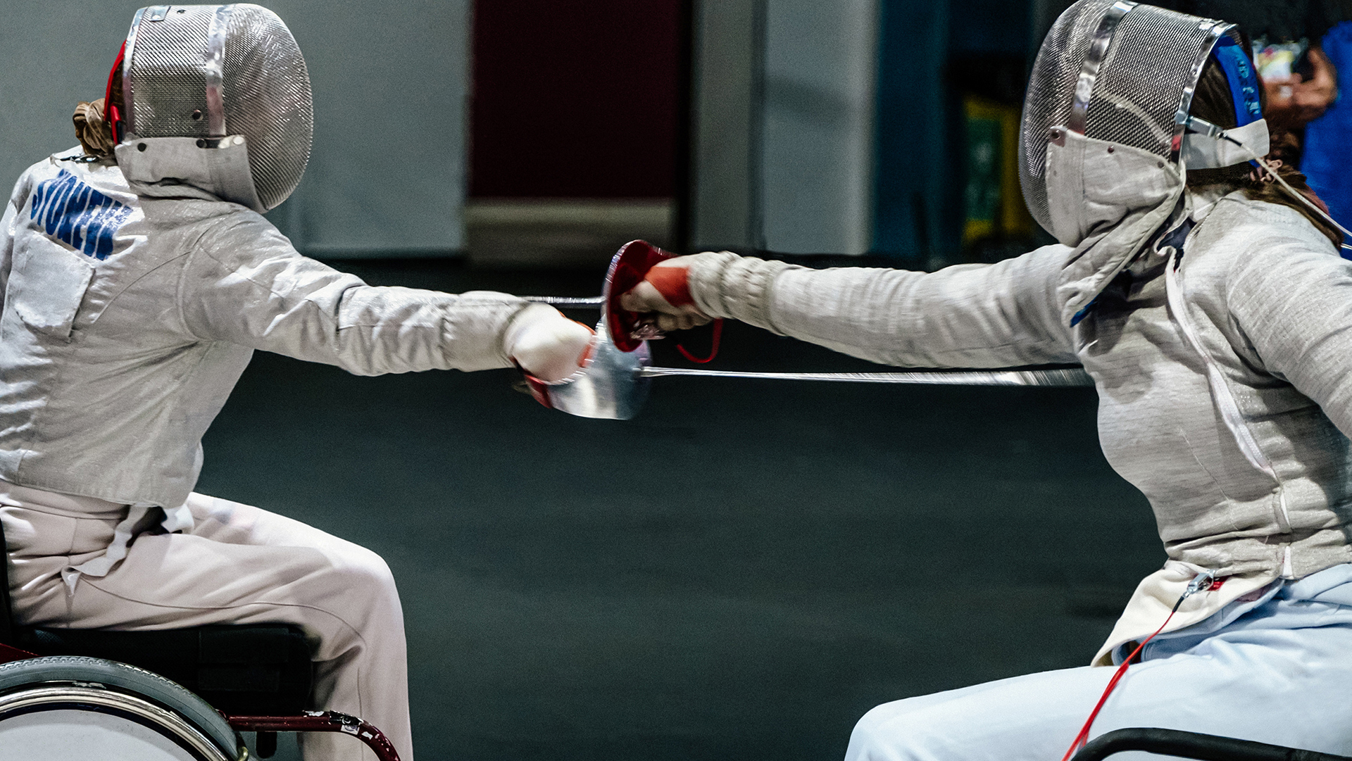 Two athletes in wheelchairs compete in a fencing match.