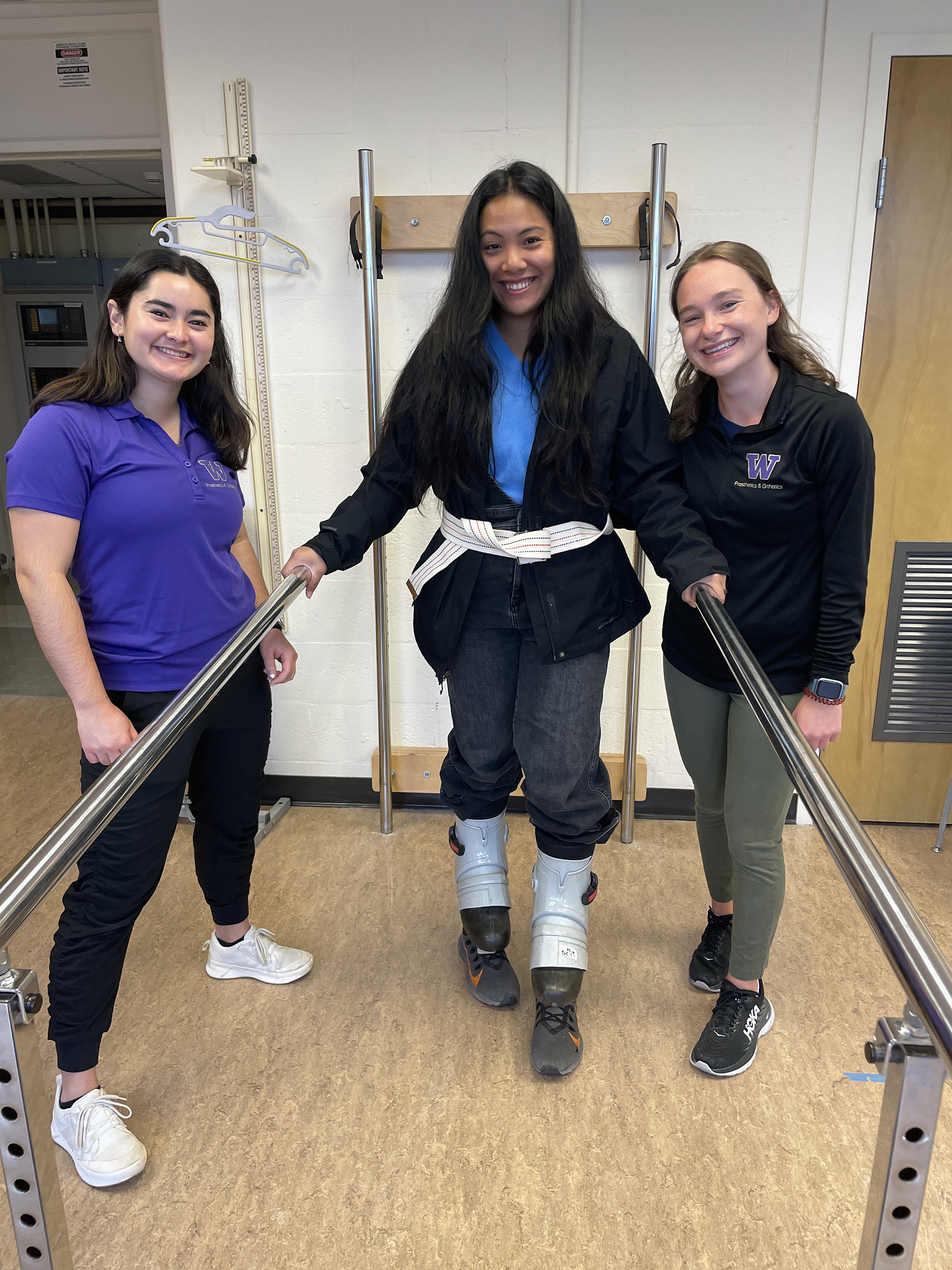 Three students stand at handrails.