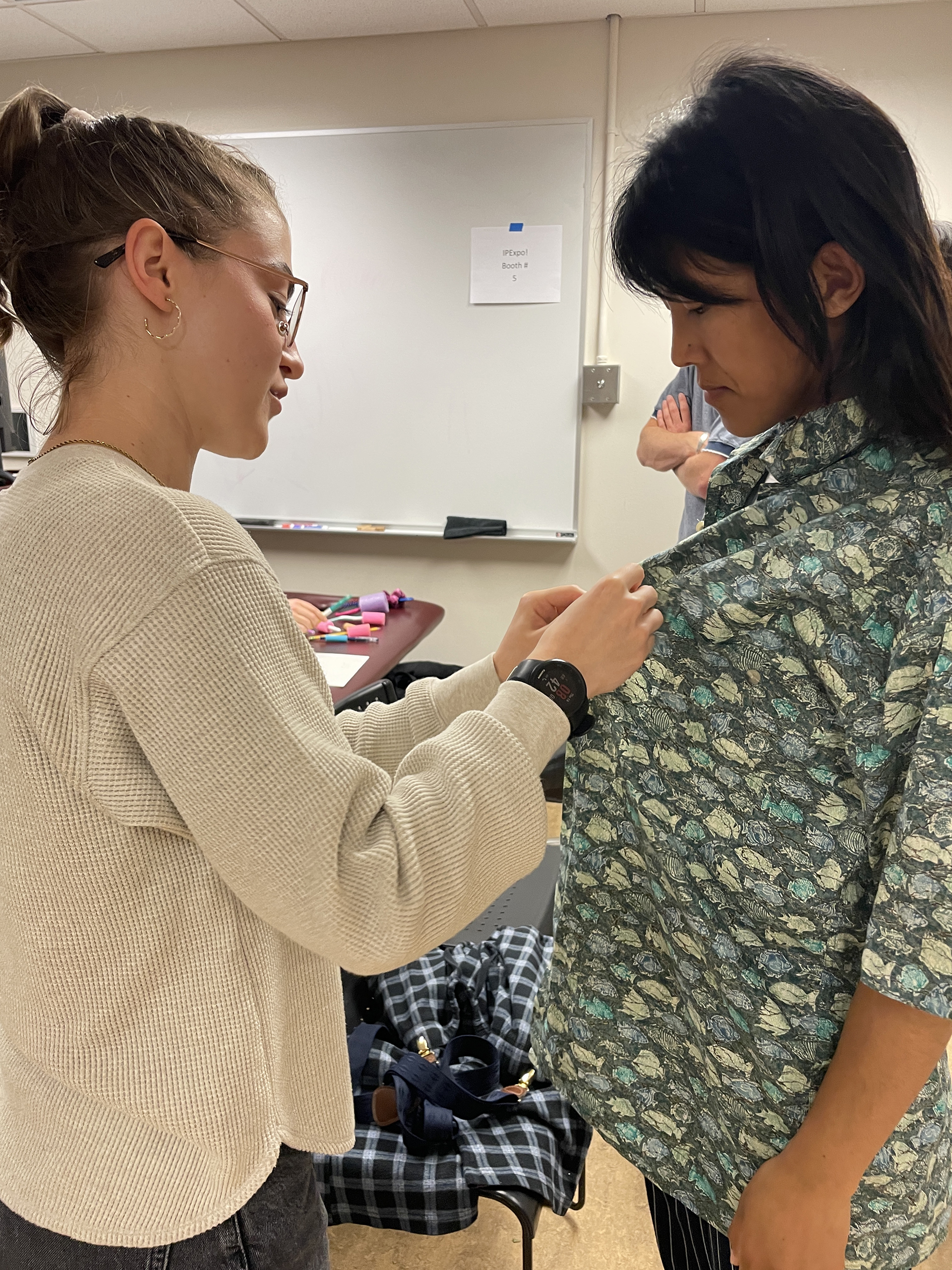 A student demonstrates assisting a patient with buttons.