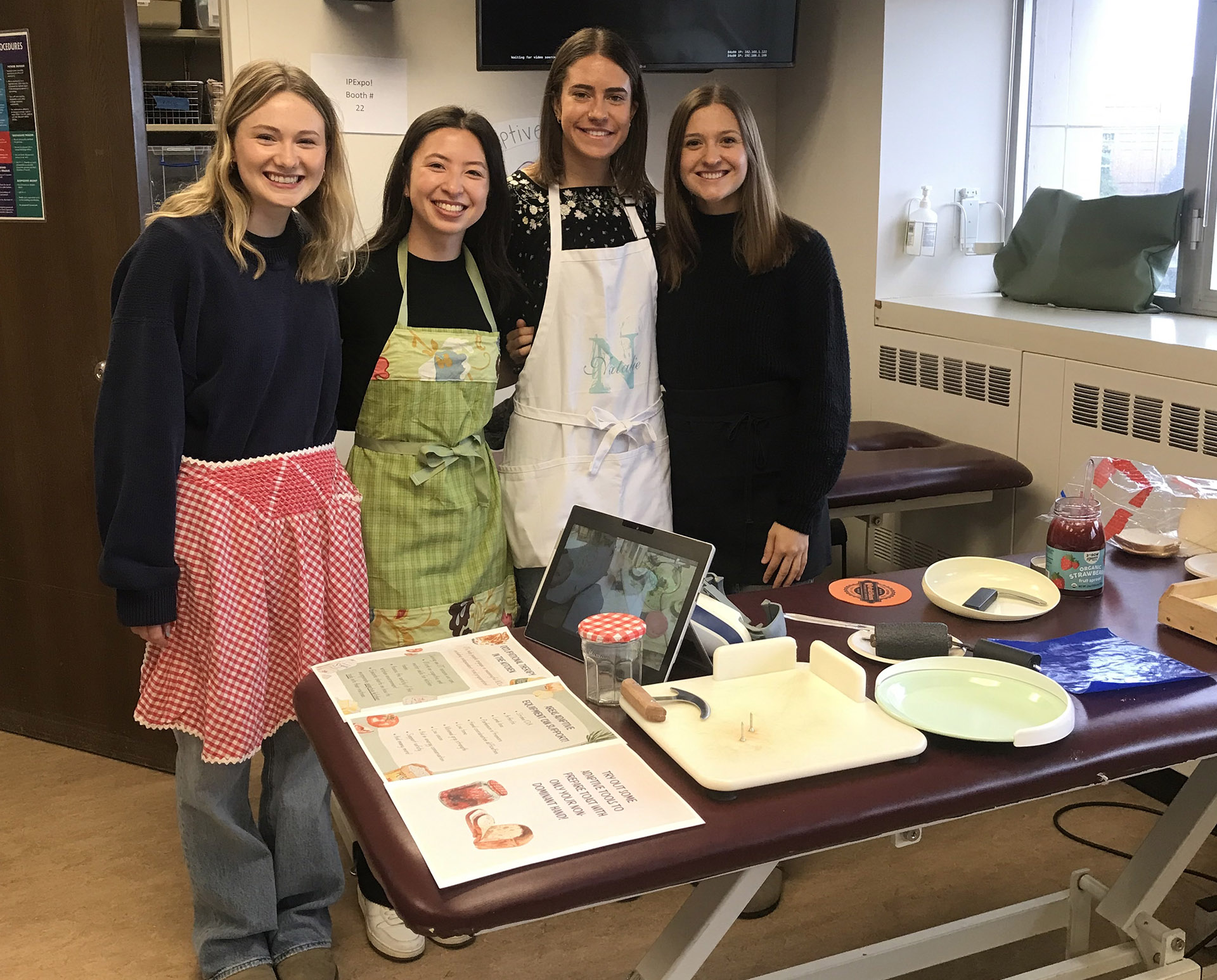 Four students stand in front of a table full of kitchen items.