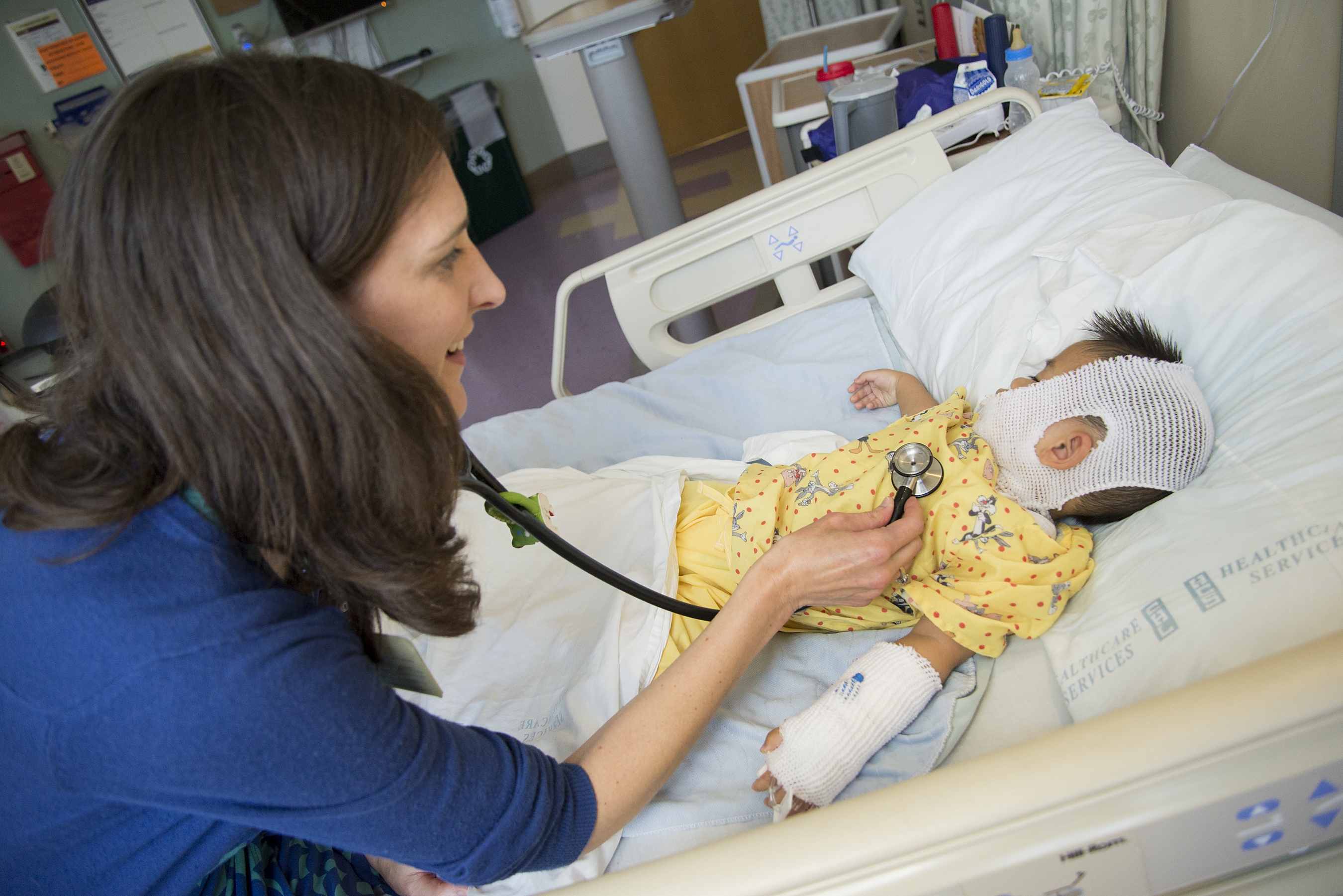 Female physician with brown hair checking a toddler with burn injuries using a stethoscope