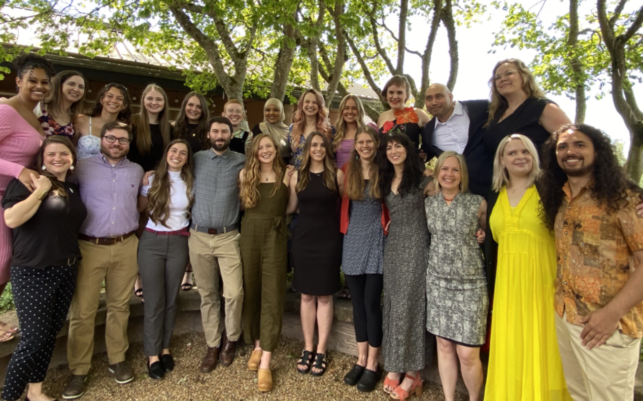 23 students gather outside on a sunny day.