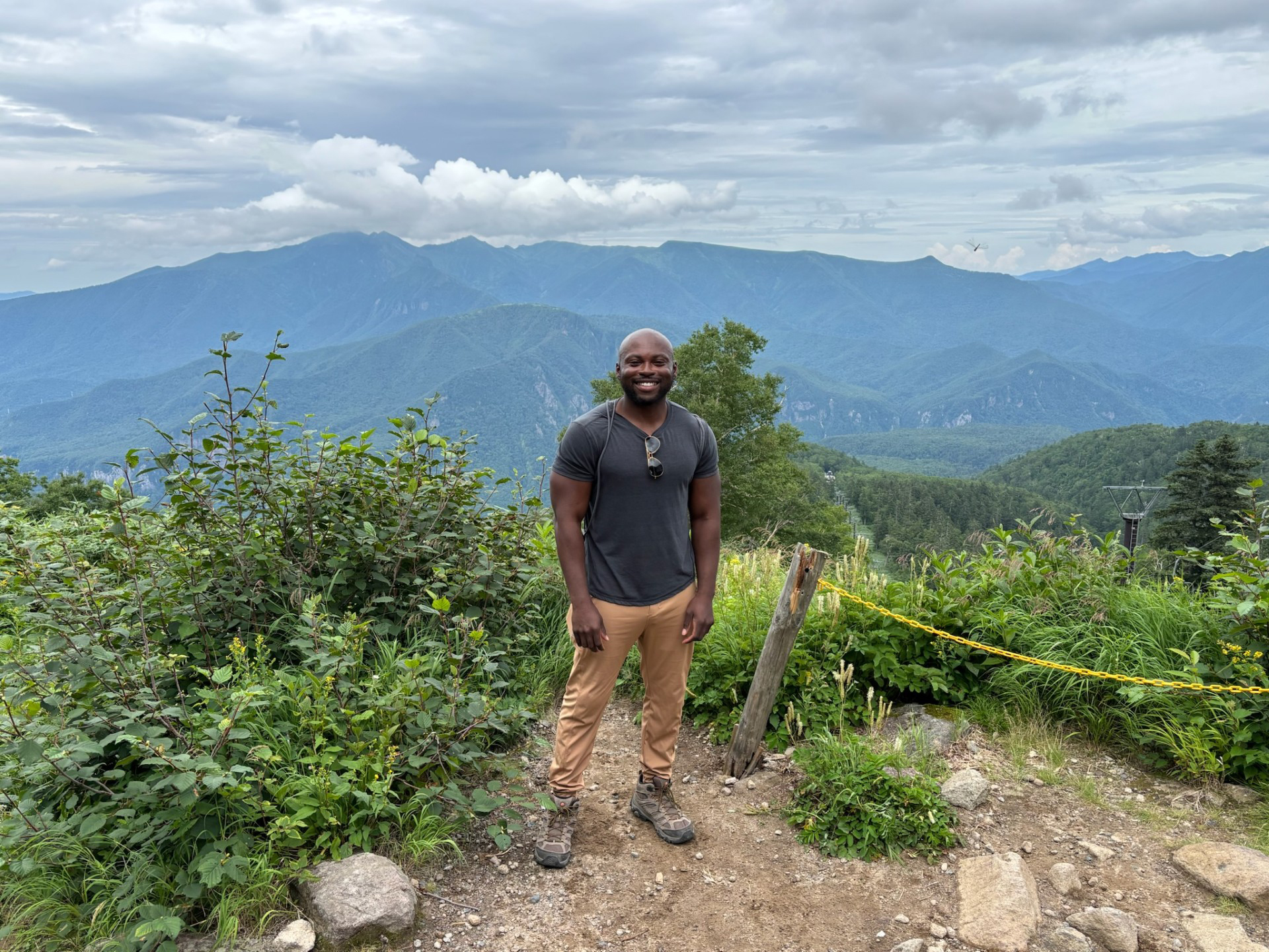 Dr. Sokunbi stands in front of a forested vista.