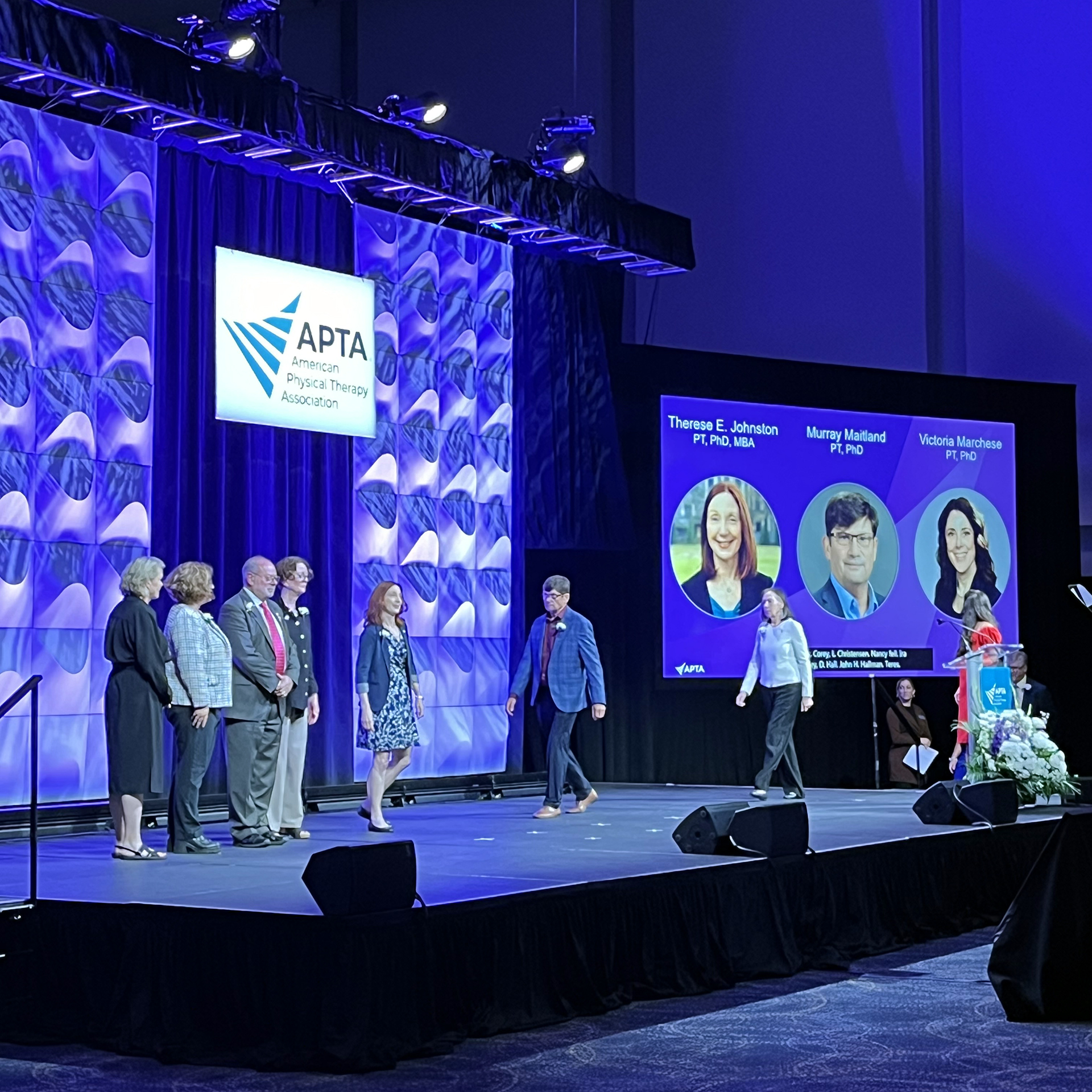 Murry Maitland walks across a convention stage with other award recipients.