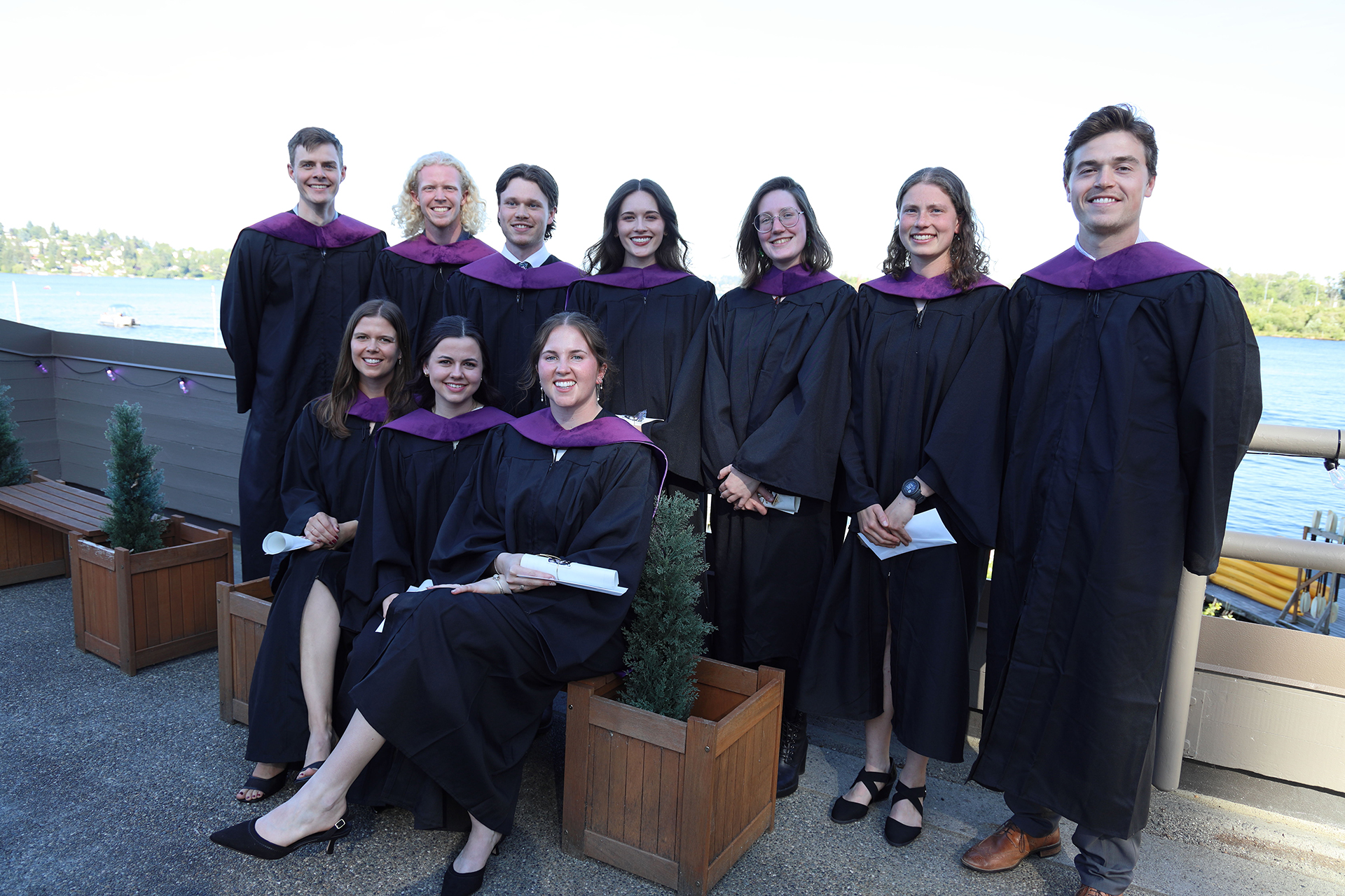 A group of people in graduation gowns smile at the camera.