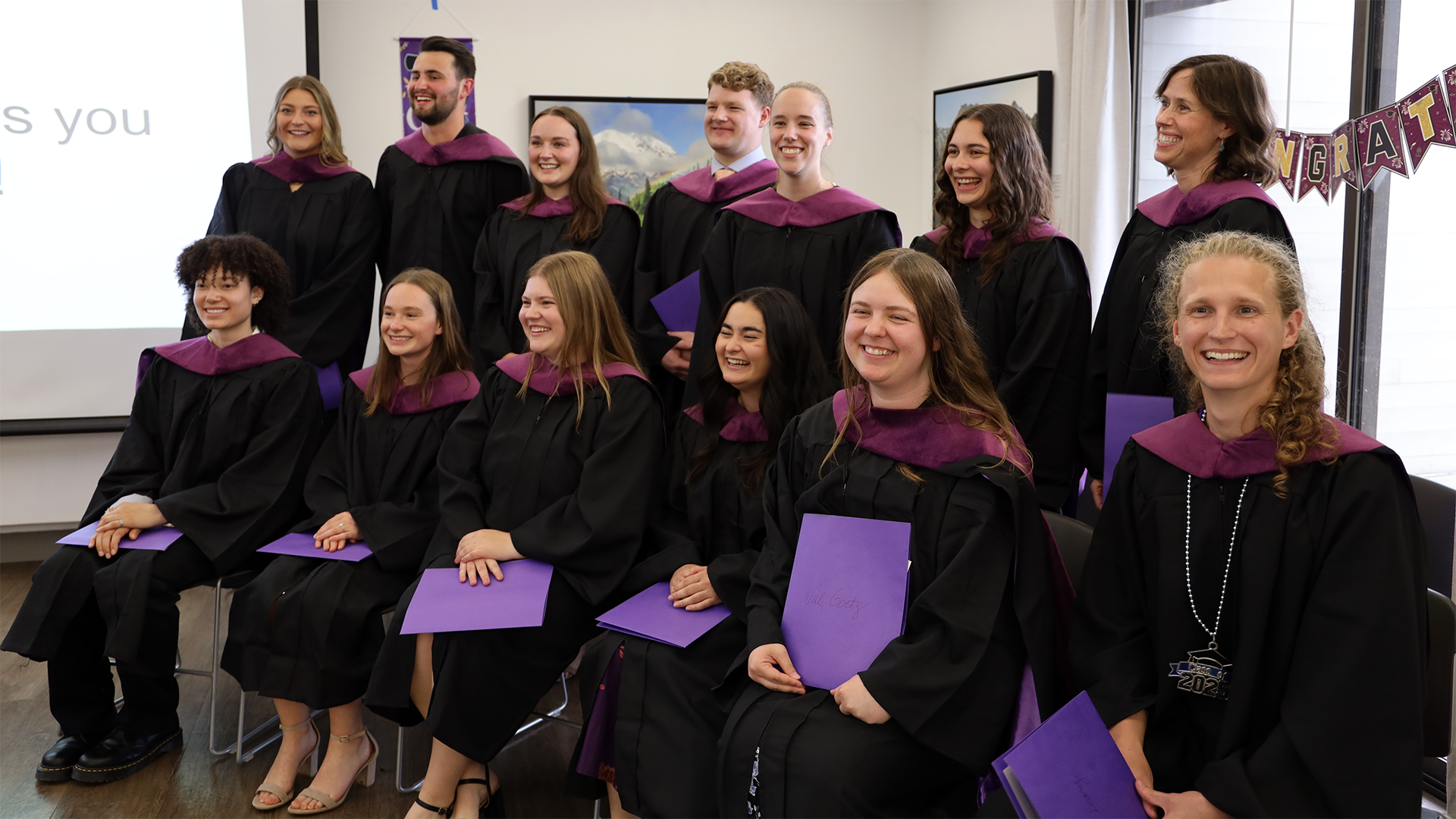 A group in graduation regalia laugh together.