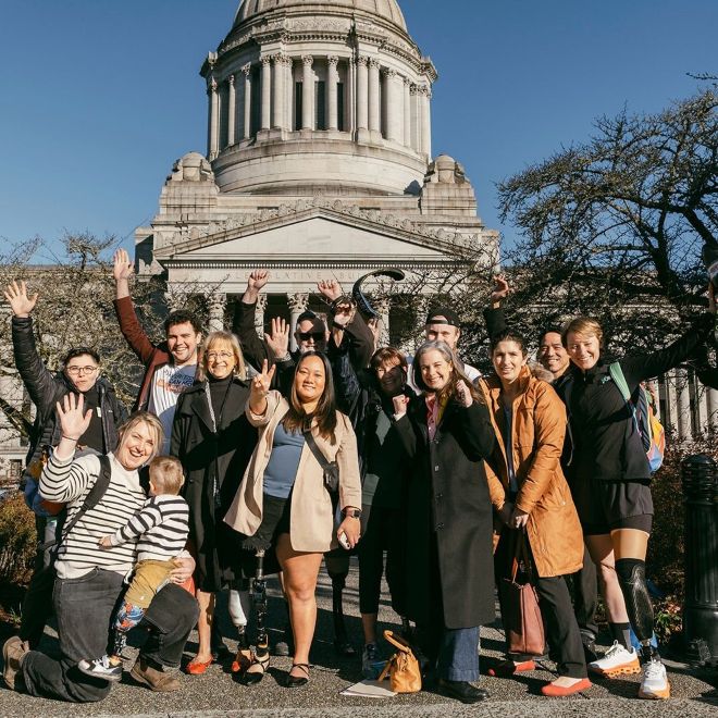 Members of the So Every Body Can Move click a picture outside of the Washington State building.