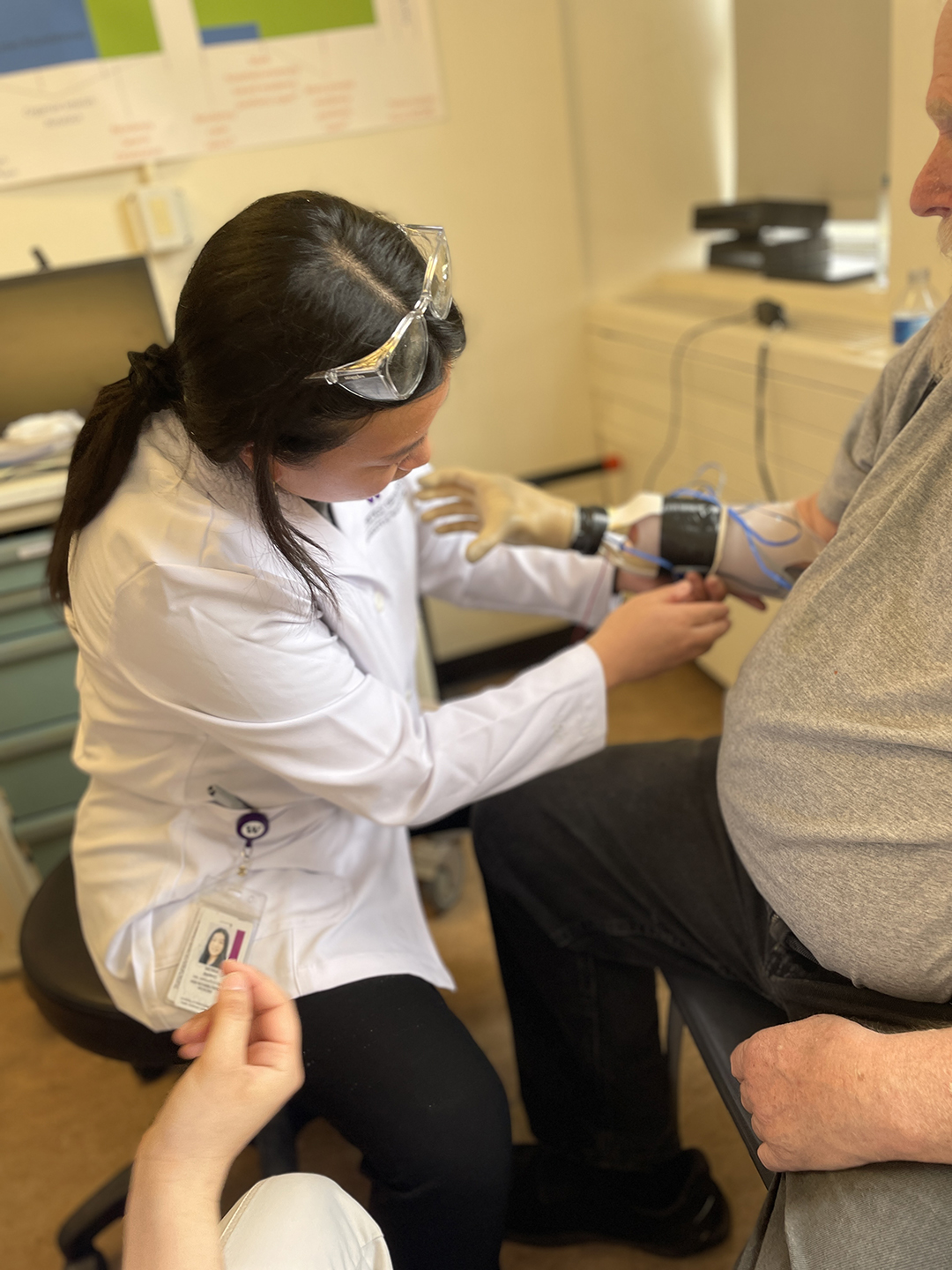 A woman adjusts wires on a man's arm prosthetic.