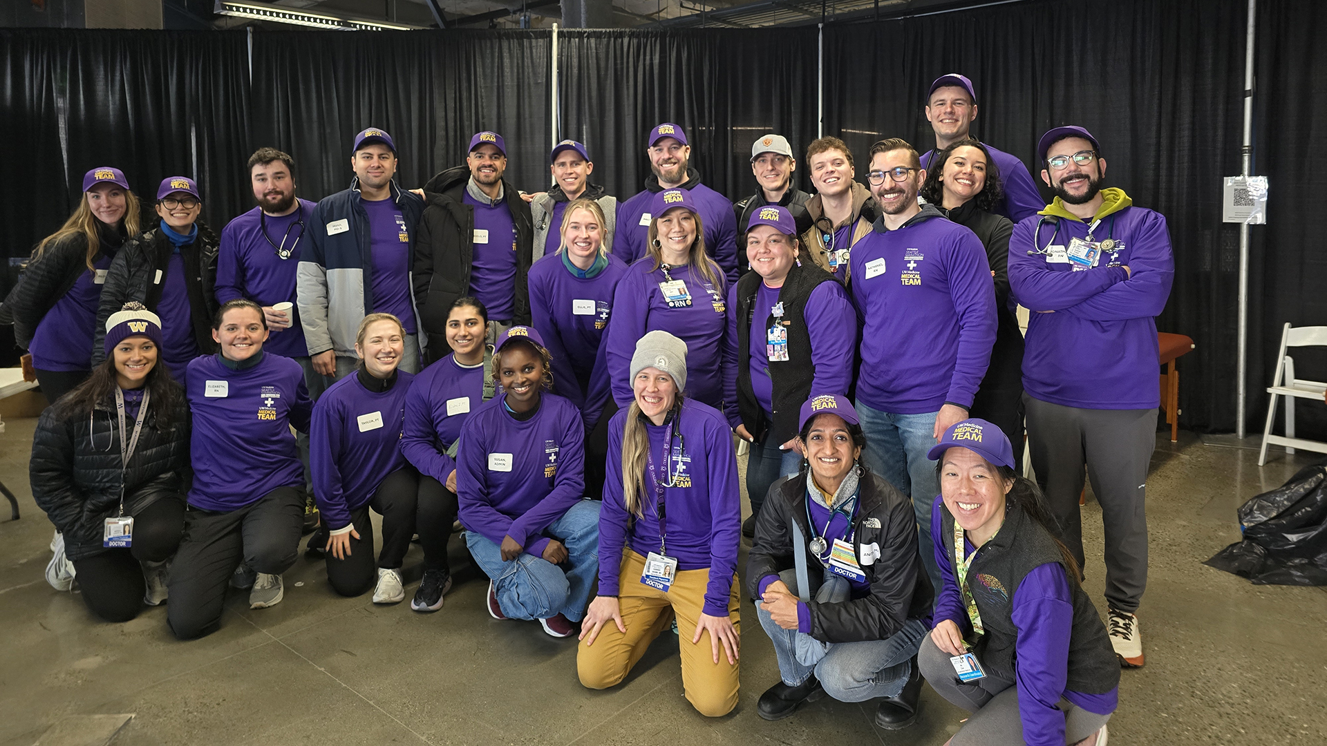 A group of people in purple shirts pose for the camera
