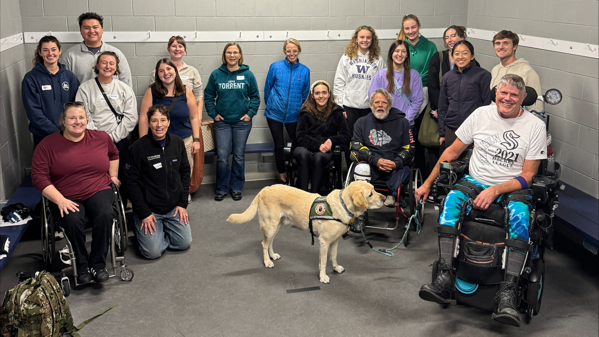 A group of diverse people and one service dog smile at the camera.