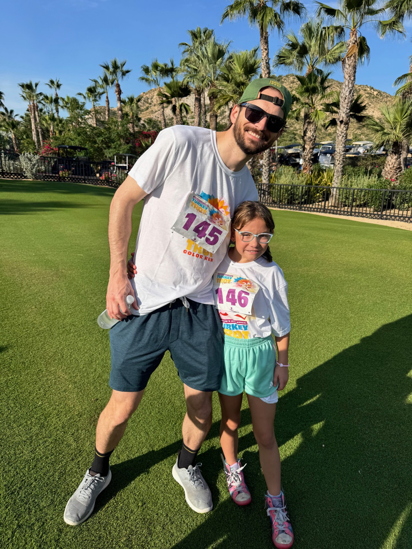 Dr. McMullen and his daughter wear running gear and stand in front of palm trees on a sunny day.