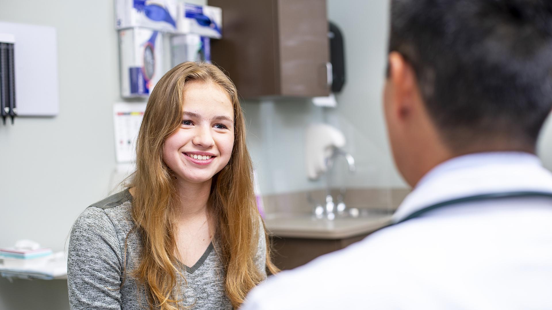 A patient smiles while talking to a doctor in a white coat.