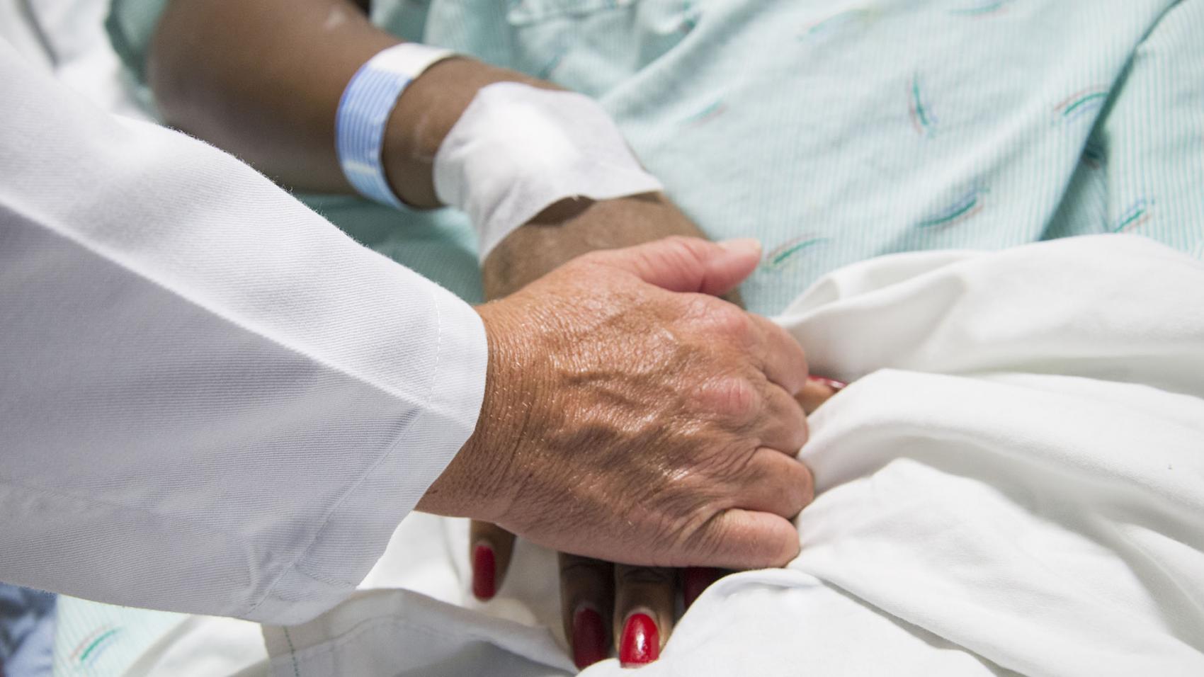 A provider holds a burn patient's hand. 