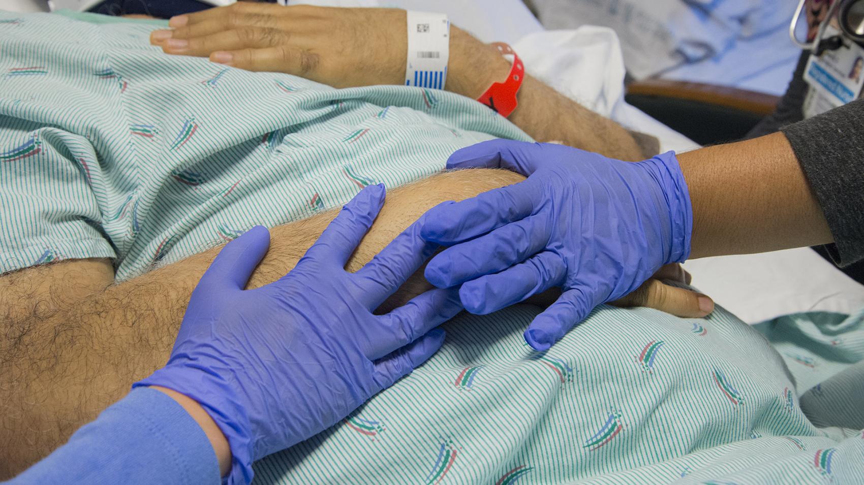 A nurse holds a patient's hand on the Inpatient Rehabilitation unit at Harborview Medical Center.