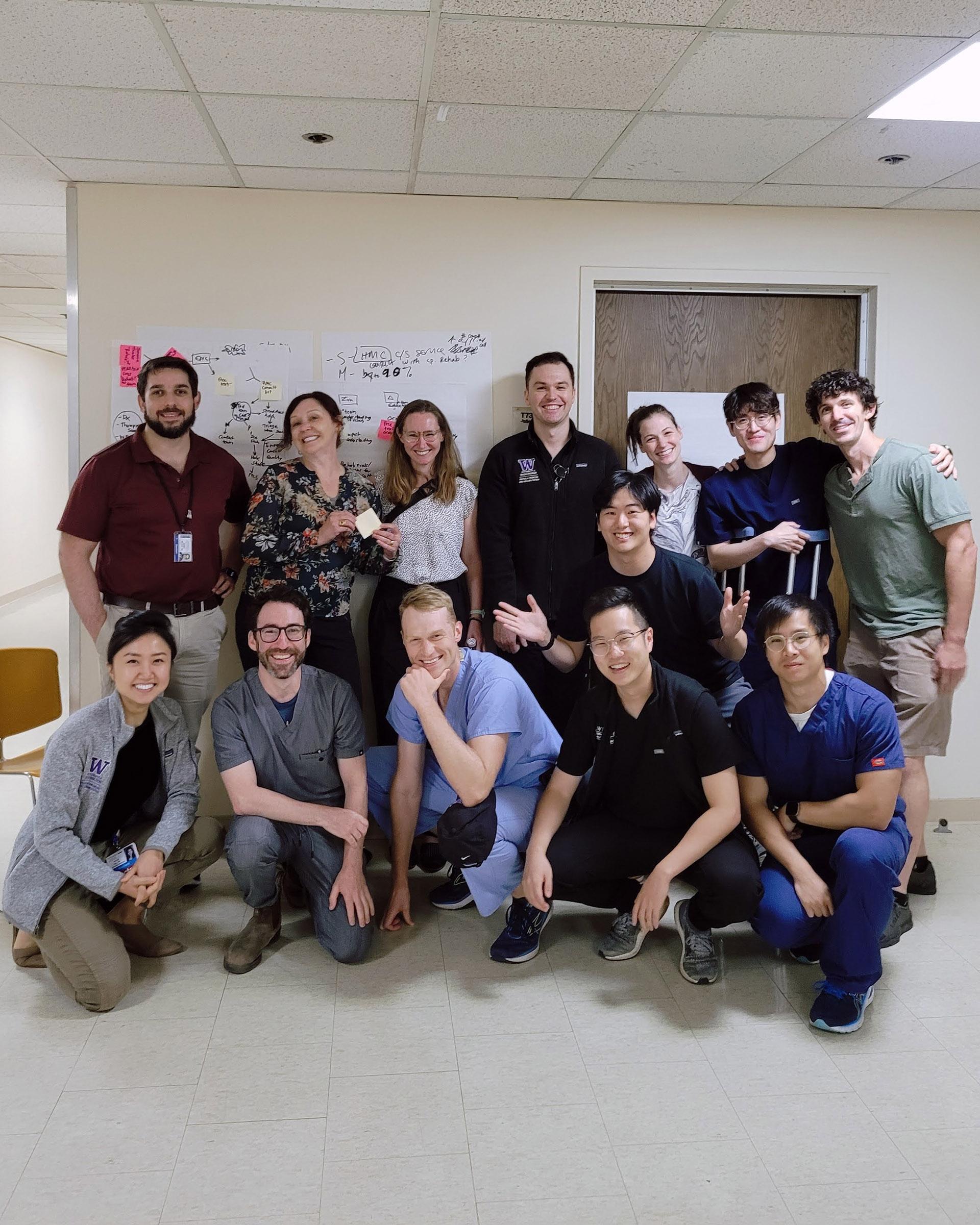 Residents in scrubs pose against a hospital wall. 