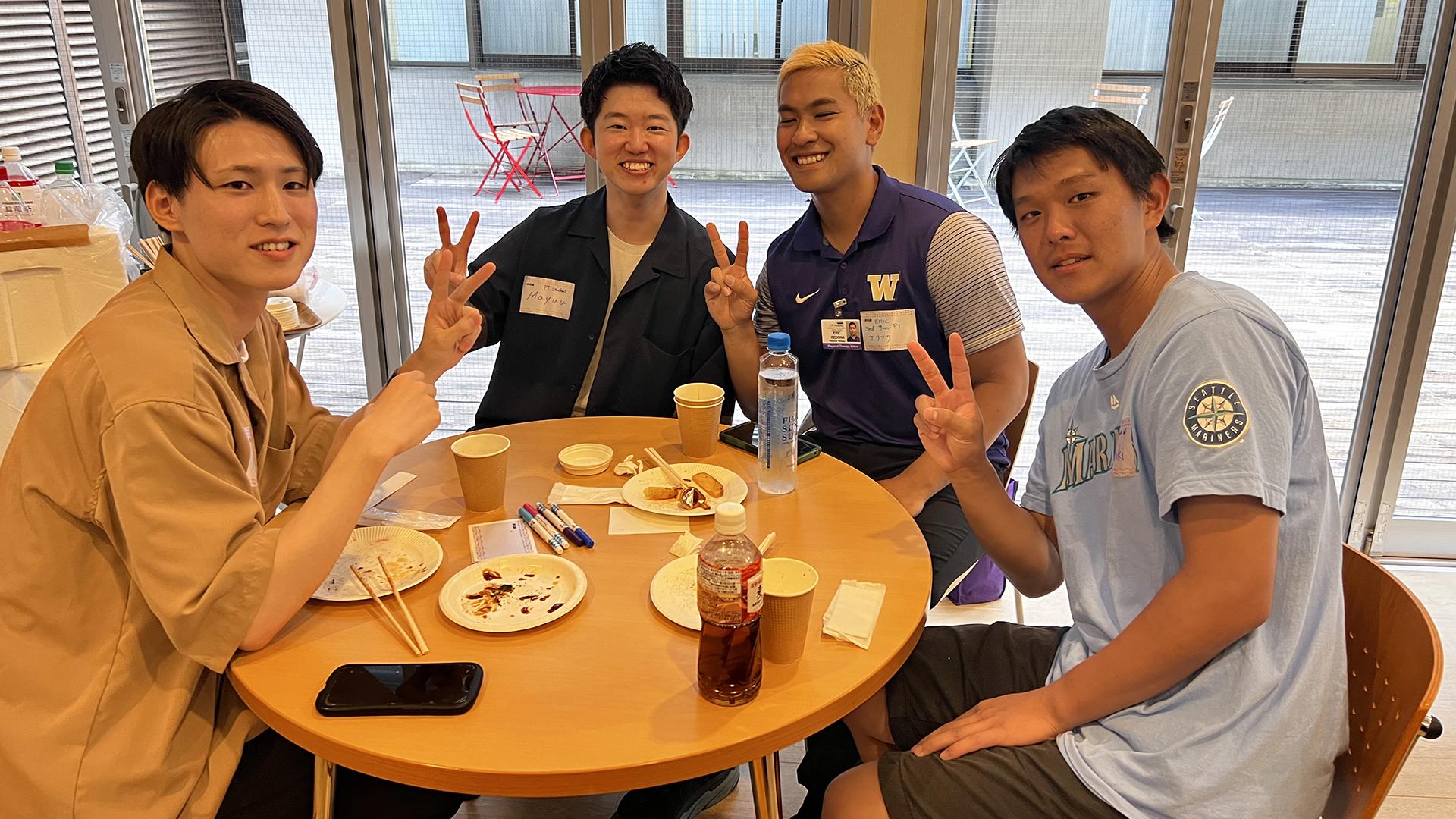 Students pose around a lunch table.