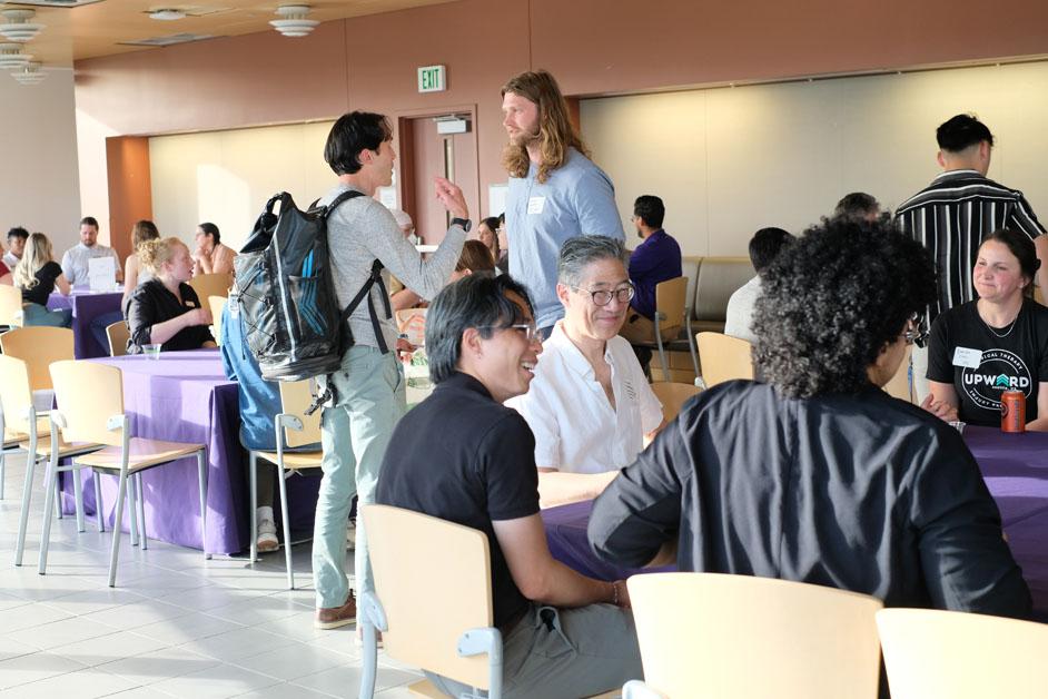 People mingle in a large meeting room. 
