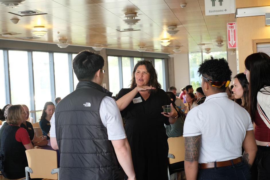 People stand and talk in a busy meeting room. 