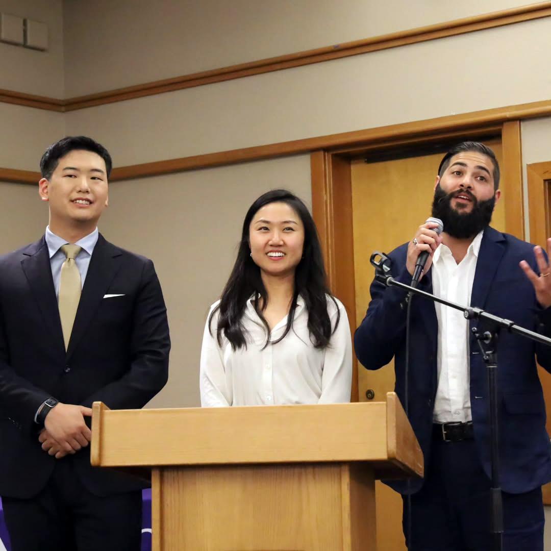 Three people stand at a podium. 