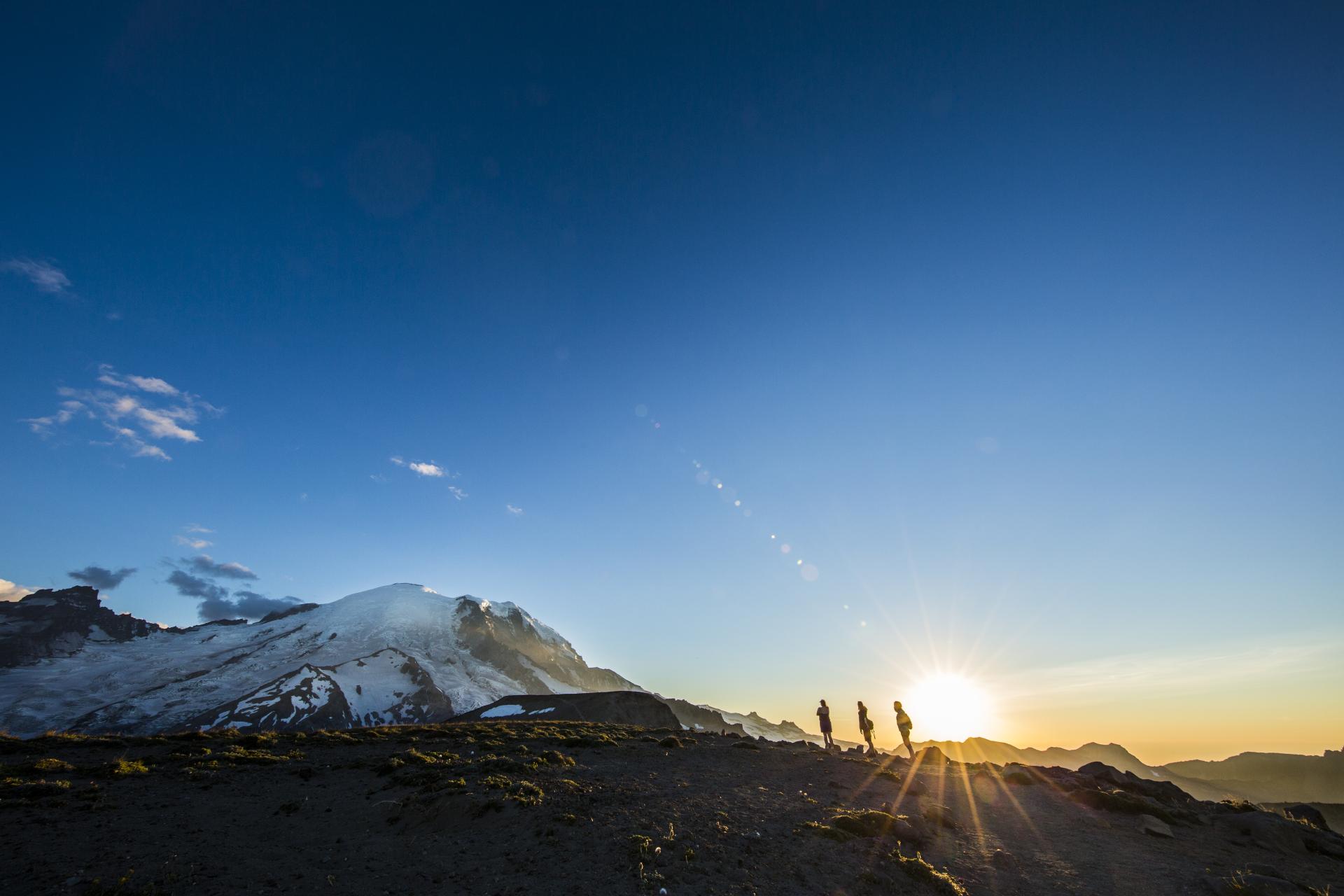 Three mountaineers ascending Mt. Rainier at sunrise