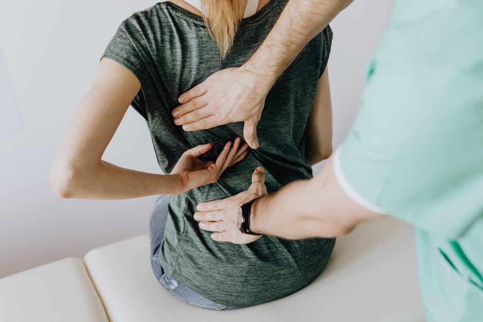 A doctor examining his patients back and spine.