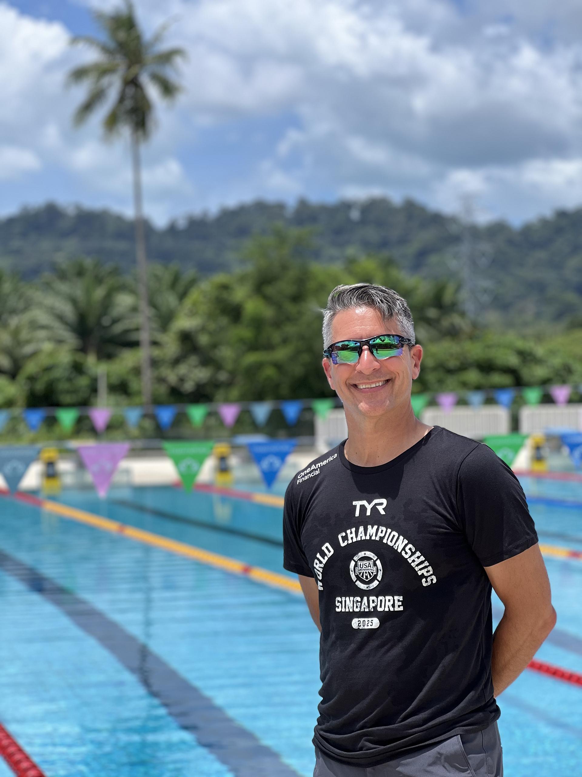 Brian Krabak stands in front of on outdoor pool on a sunny day. 