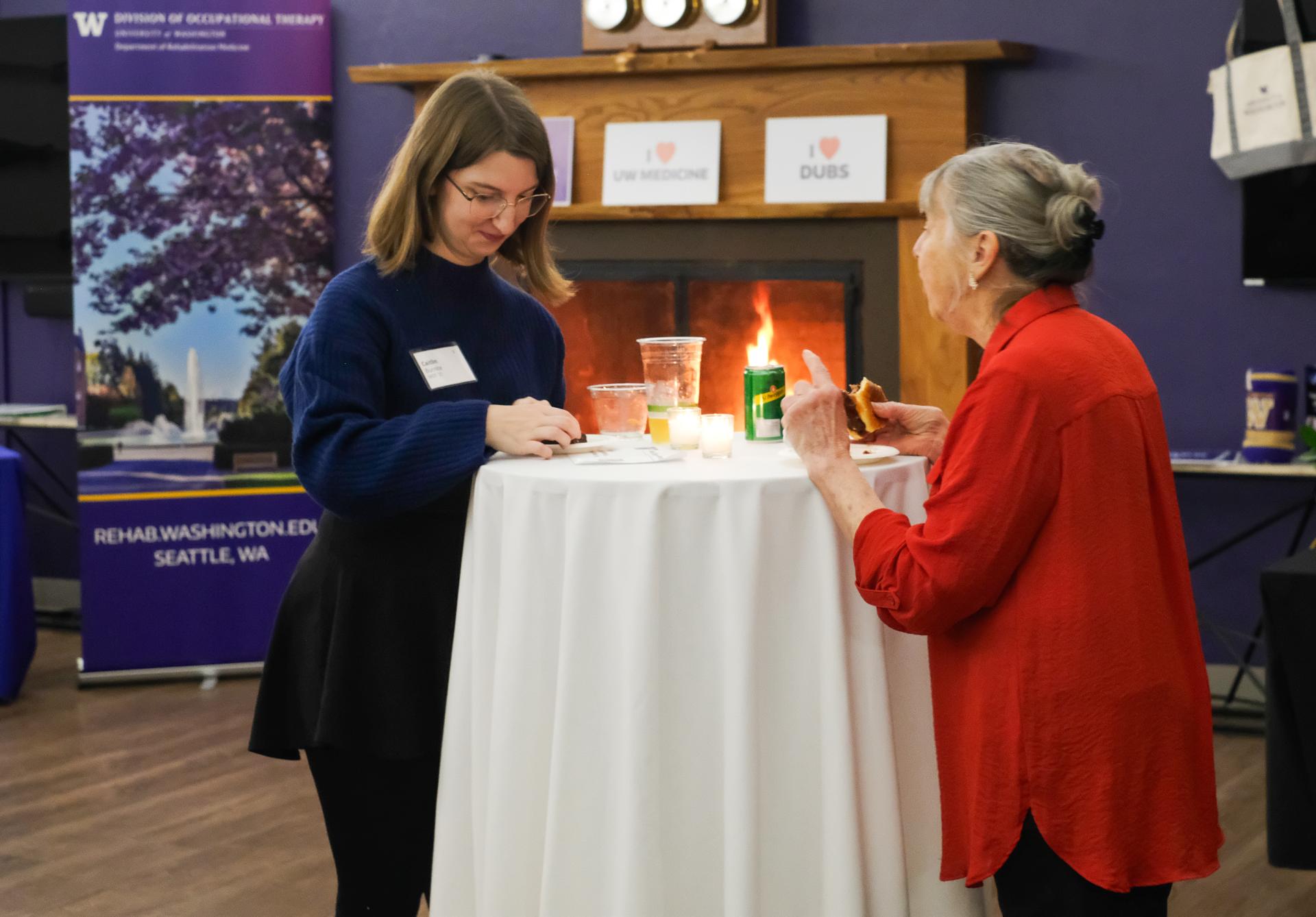 Retired professor and alum talking and eating at a round table.