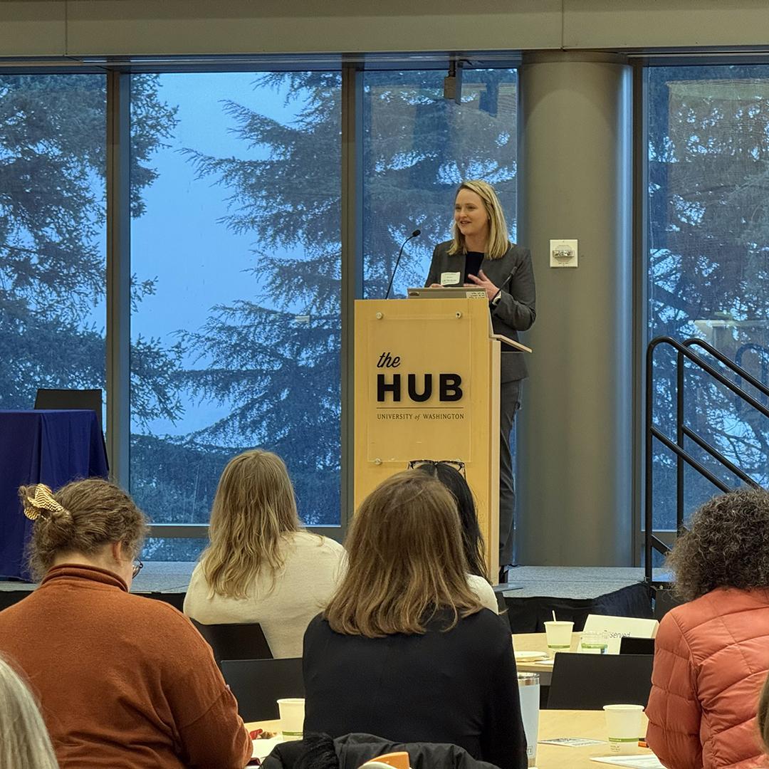 A woman speaks at a podium in front of a crowd. 
