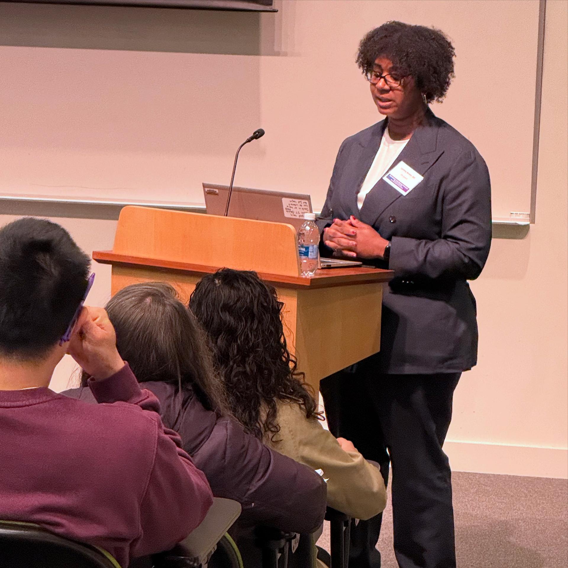 A woman speaks to a crowd from a podium.