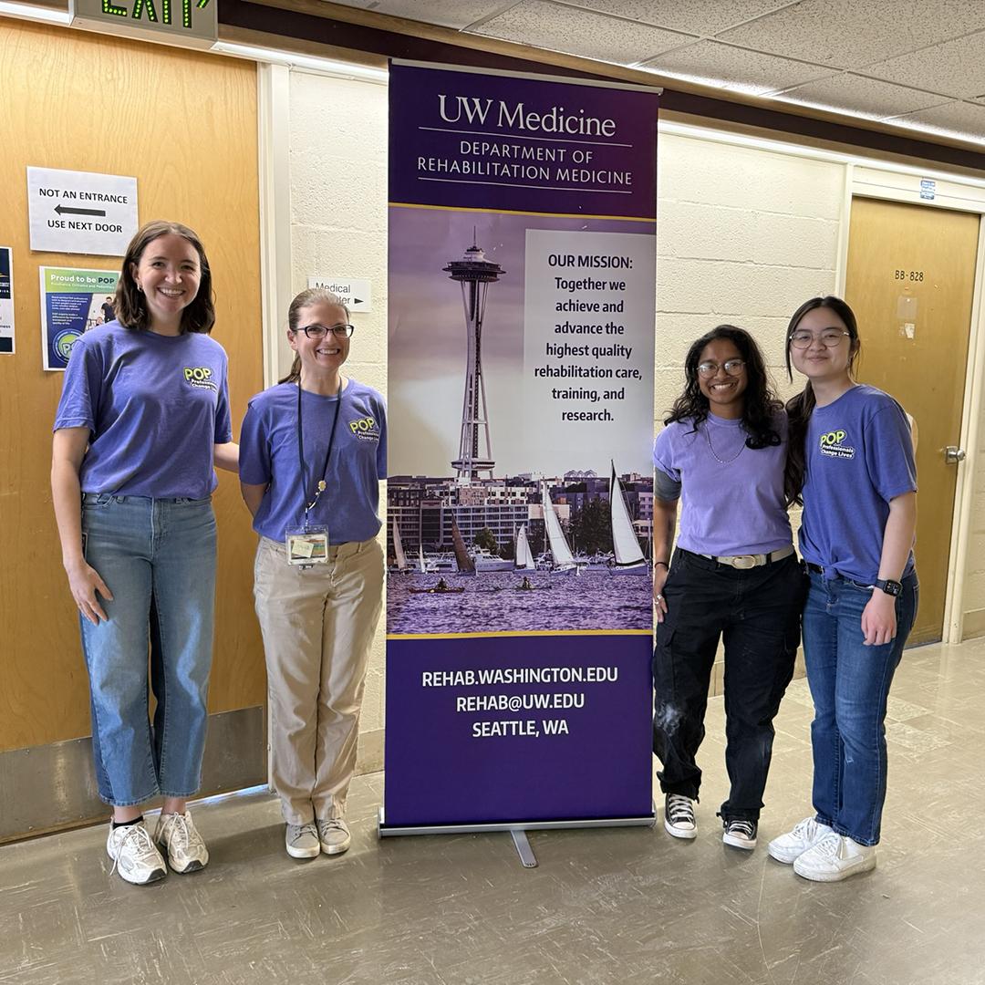 People stand next to a purple banner and smile. 