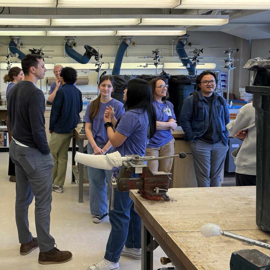 People stand talking in a lab full of large equipment. 
