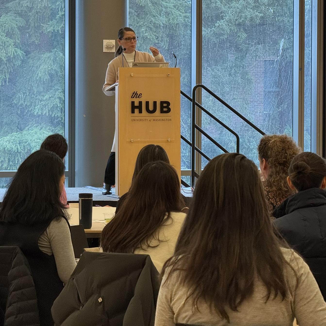 A crowd is listening to a woman speak at a podium. 
