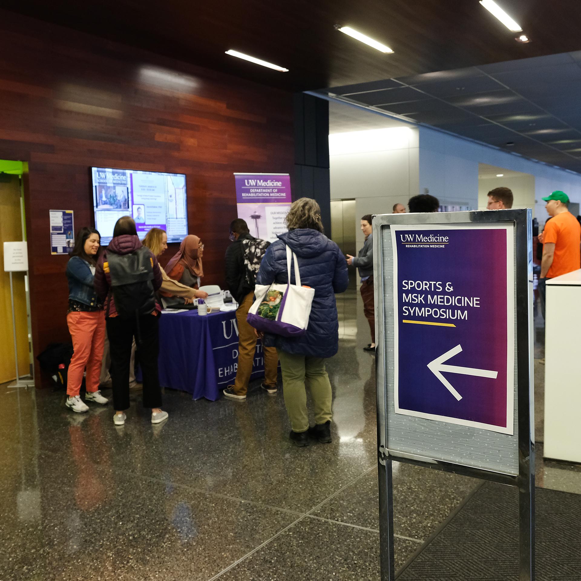 People sign in at an event welcome table. 