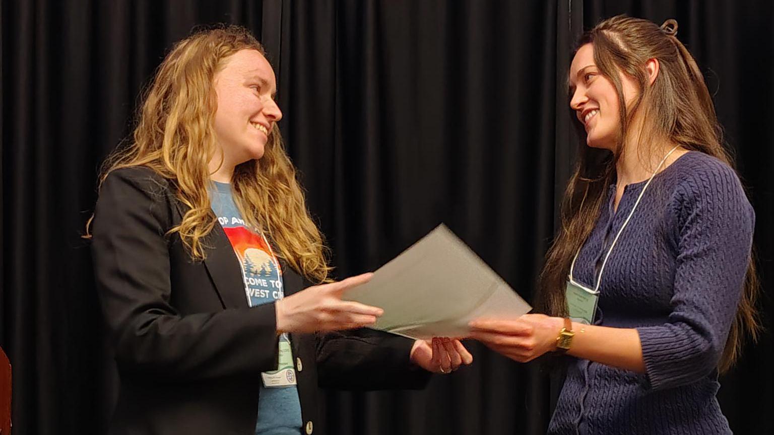 A woman accepts a certificate on a stage. 