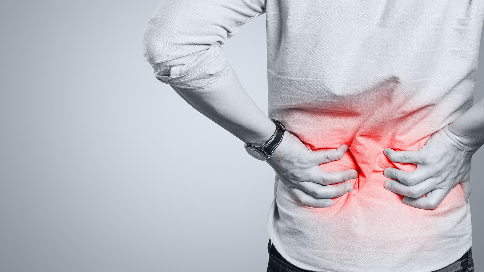 A black and white photo of a person clutching their lower back, with red radiating out of their spine.