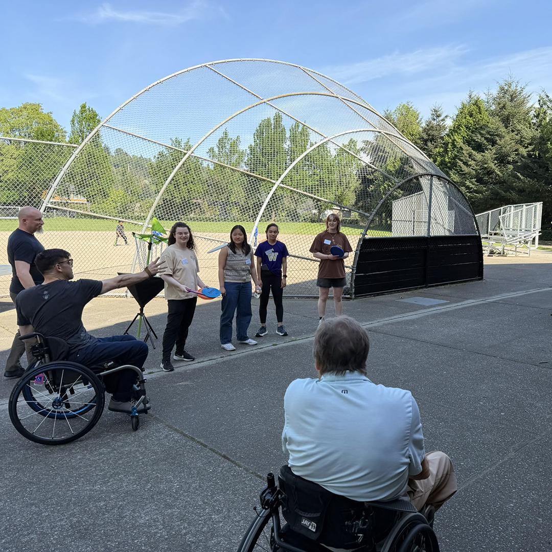 A man in a wheelchair gets ready to throw a frisbee at a target.