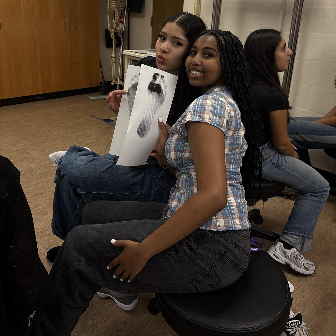 Two students hold up ink footprints.
