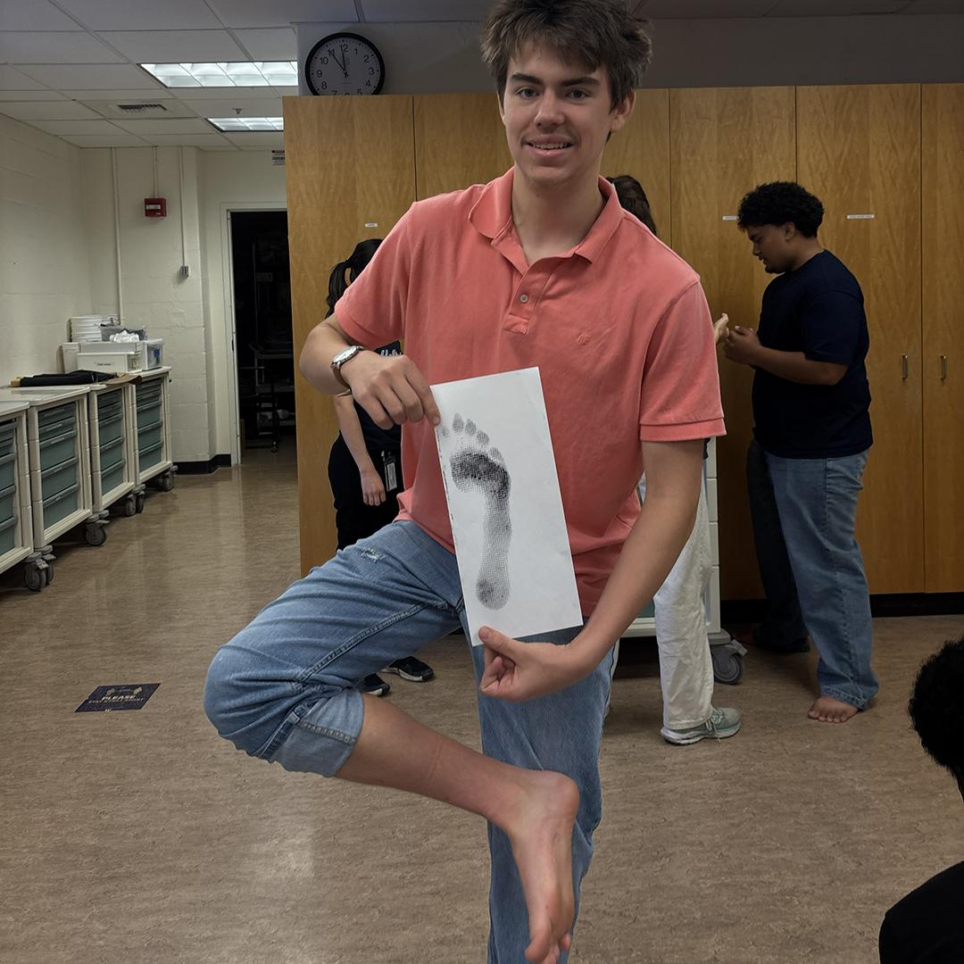 A stduent holds up an ink footprint.