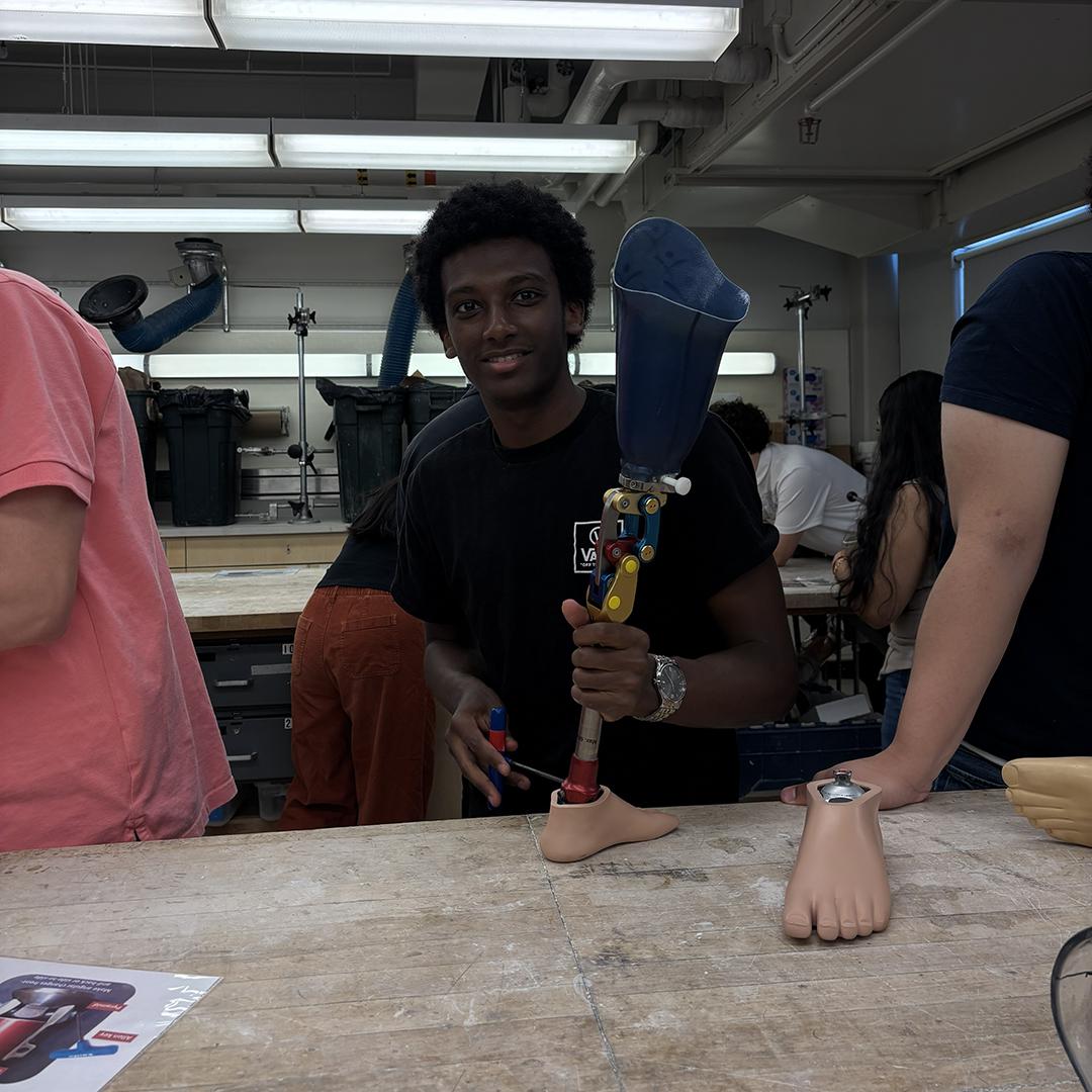 A student holds up a lower limb prosthetic.