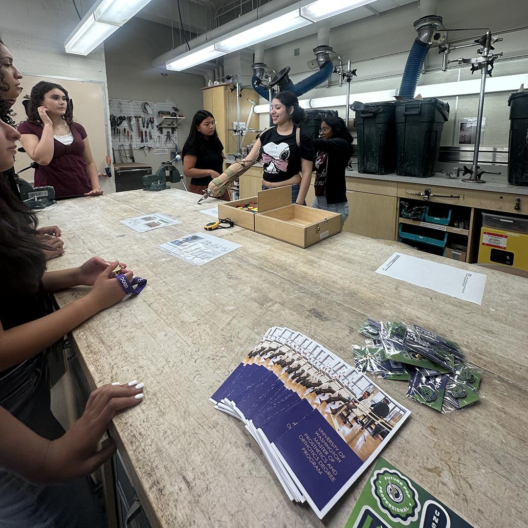 Students gather around a large workshop table.