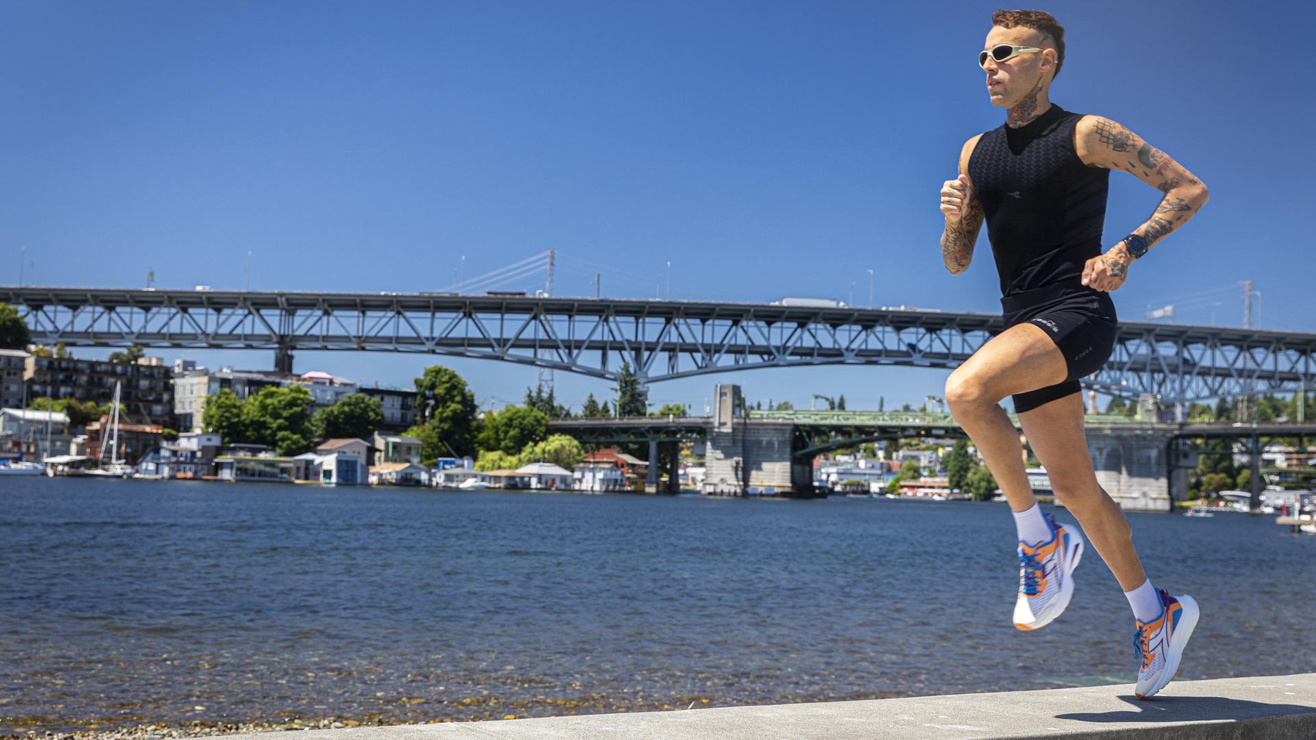 A man runs near a waterway, with a bridge in the background.